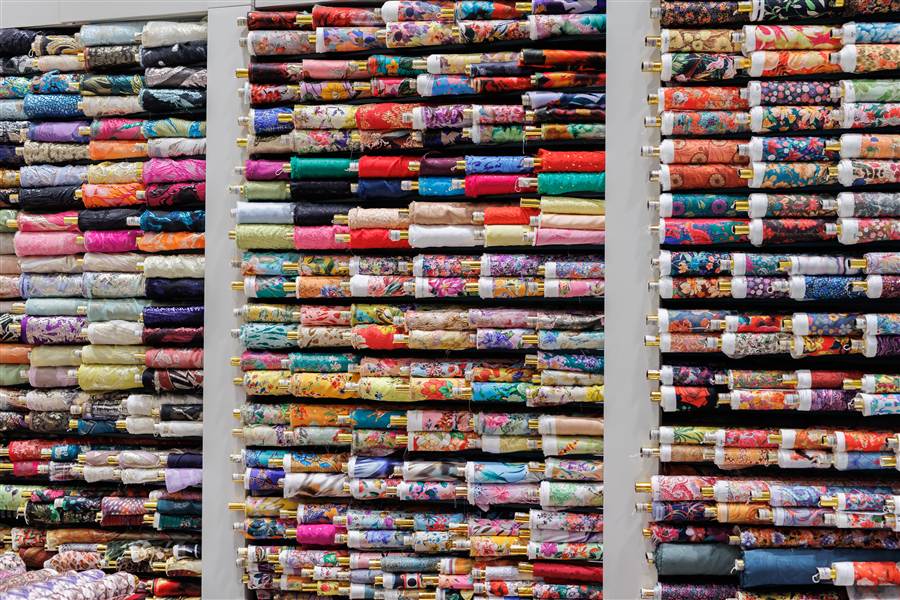 Colorful cotton fabric bolts arranged on shop shelves